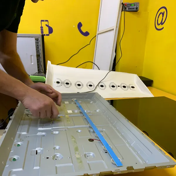 Мастер Паскаля устанавливает планку подсветки в панель телевизора